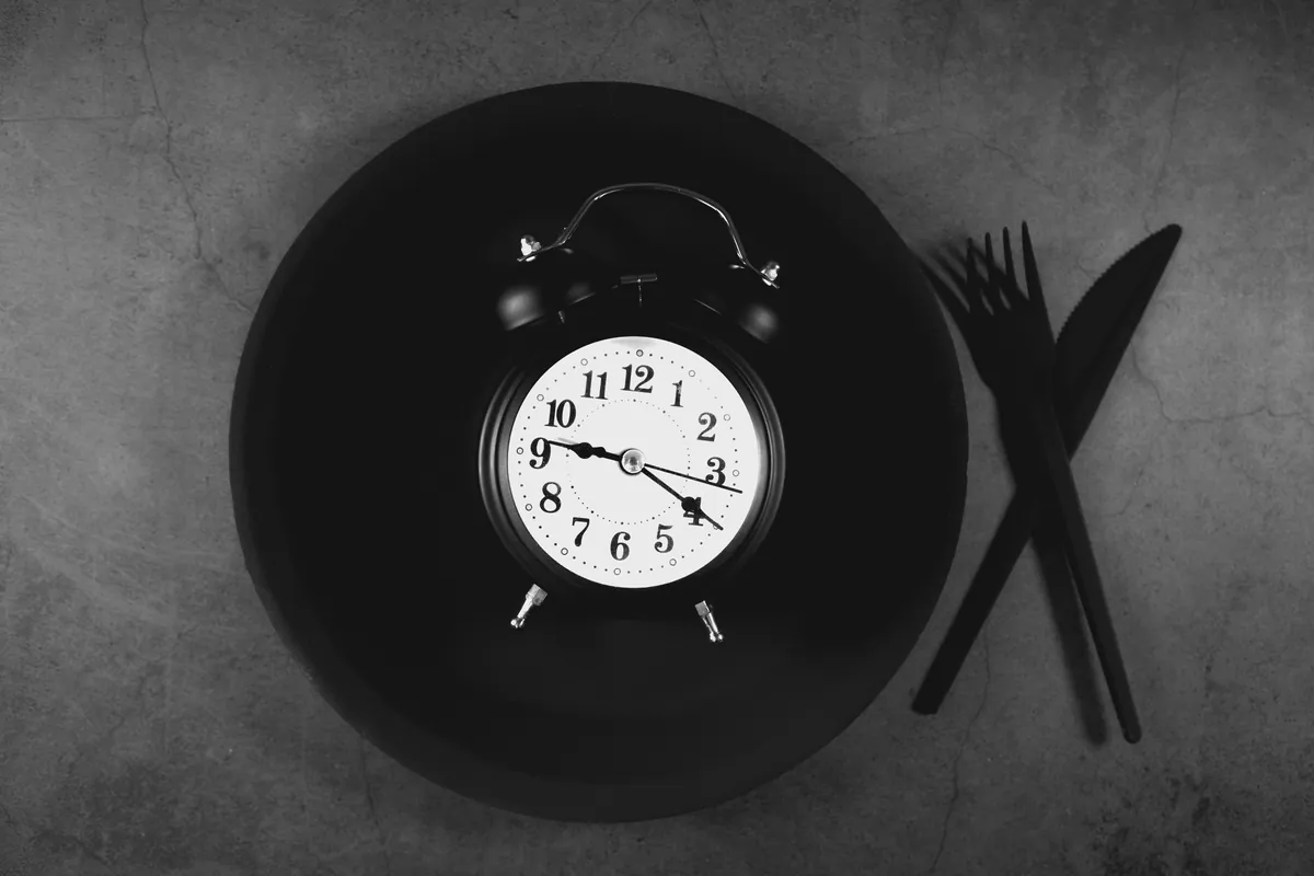 Clock and empty plate representing time-restricted eating and intermittent fasting