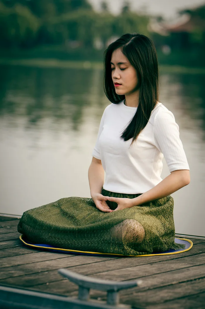 Woman meditating outdoors by the water for stress relief